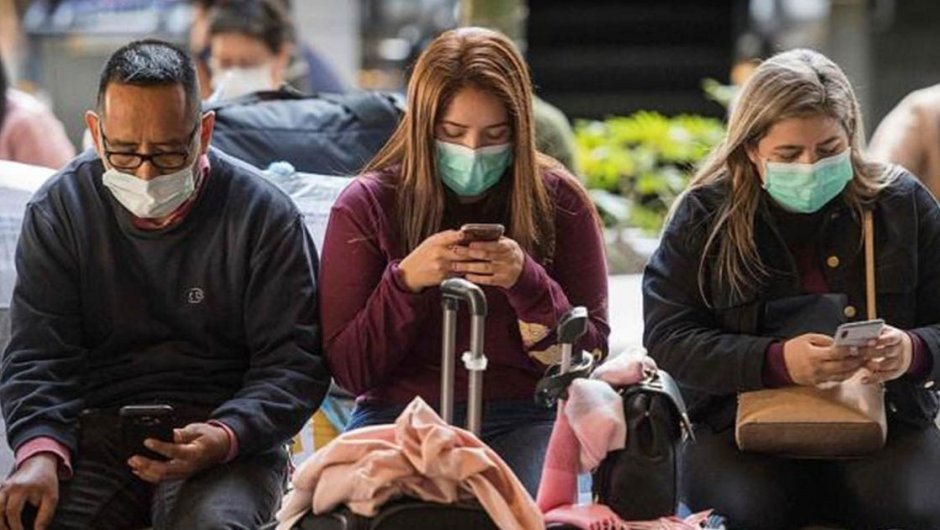 Imagen de contexto de personas viendo sus teléfonos con mascarillas por el coronavirus. (Foto: Europa Press).